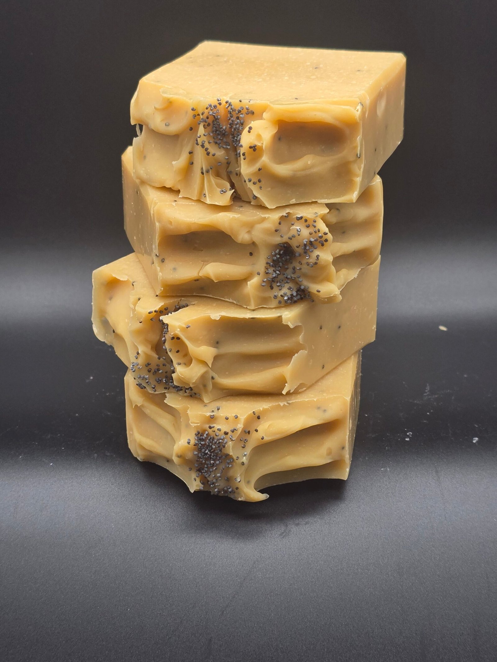 Jabón artesanal de arcilla amarilla con leche de coco y manteca de cacao, aromatizado con limón y litsea, decorado con semillas de amapola.